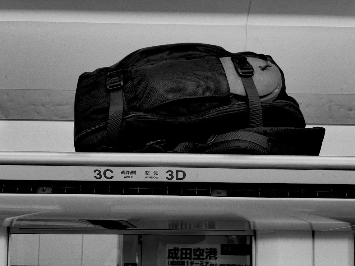 A backpack on a train shelf, which displays seat markings in English and Japanese kanji.