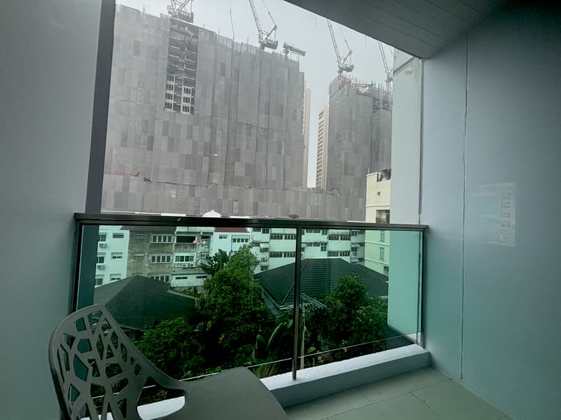 A view from a balcony overlooking two large high-rise buildings covered in scaffolding and construction cranes.
