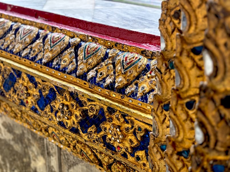 Close-up of intricate gold, blue, and mosaic architectural details at the Grand Palace in Bangkok.