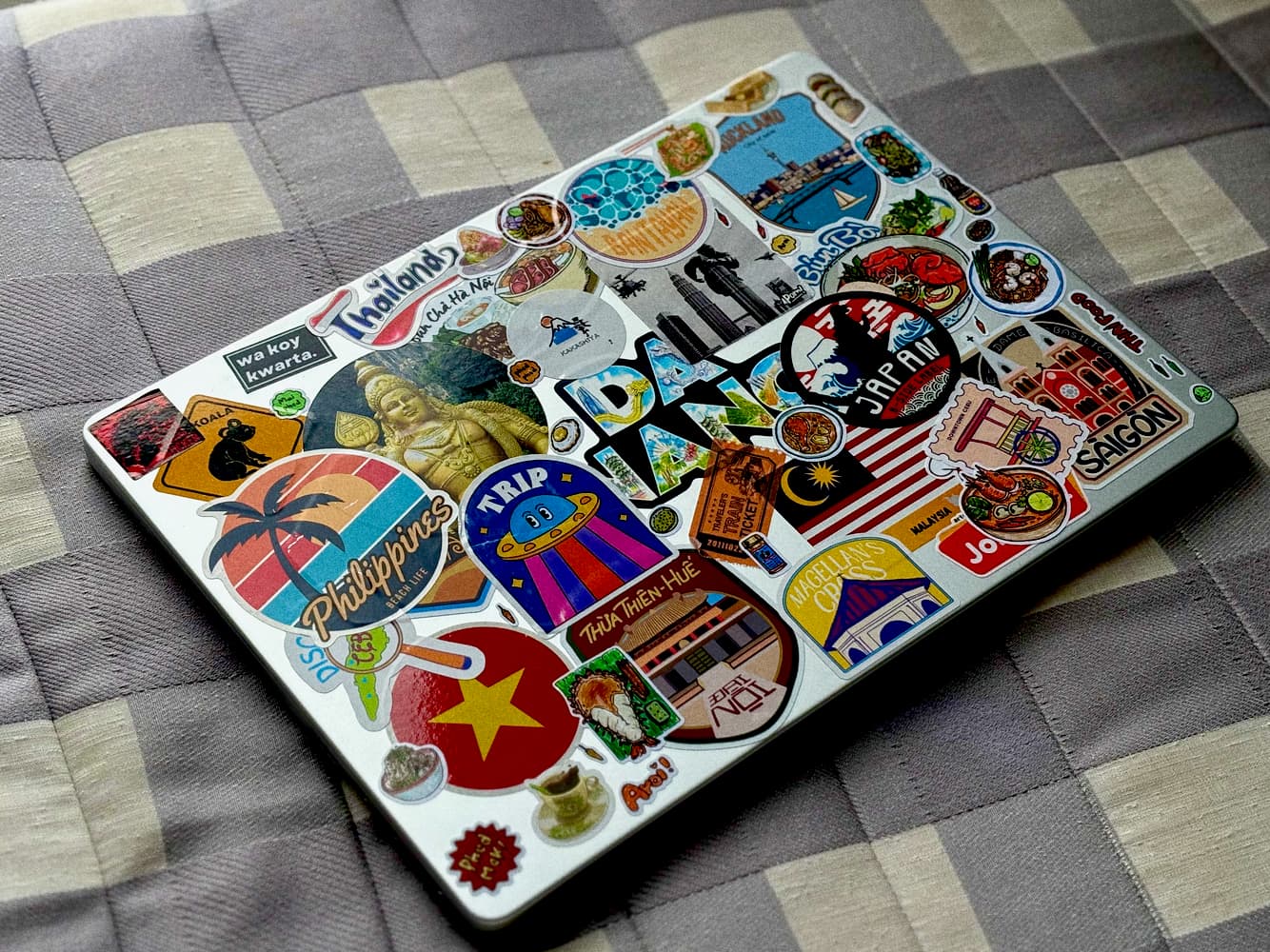 A Macbook with lots of travel stickers on the lid.